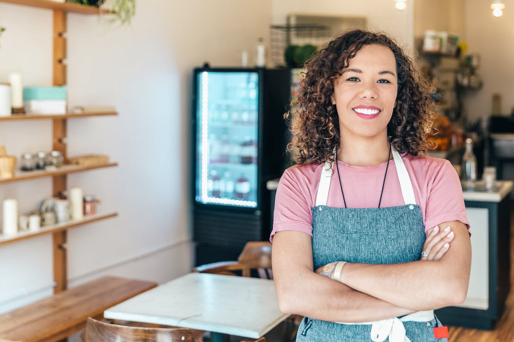 Woman wearing an apron standing in a kitchen with arms crossed